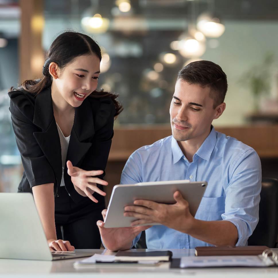 woman and man in a business meeting looking at a computer and tablet