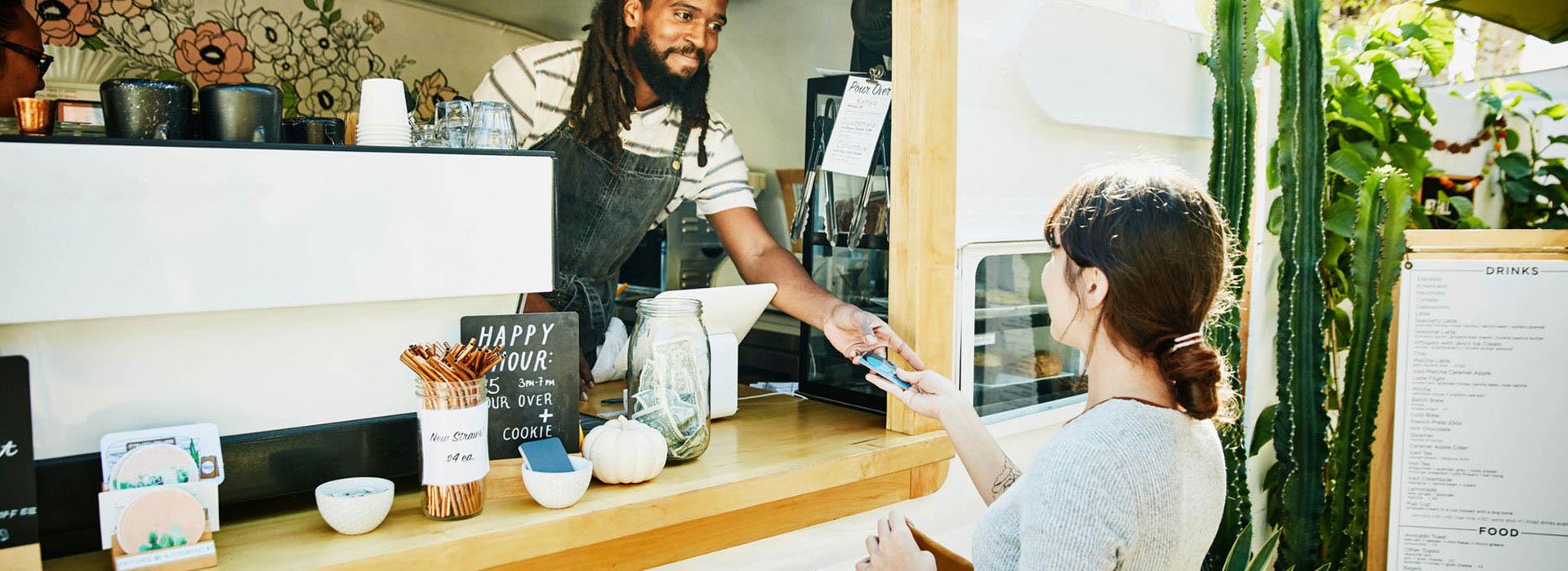 African American male barista handing Caucasian female her credit card