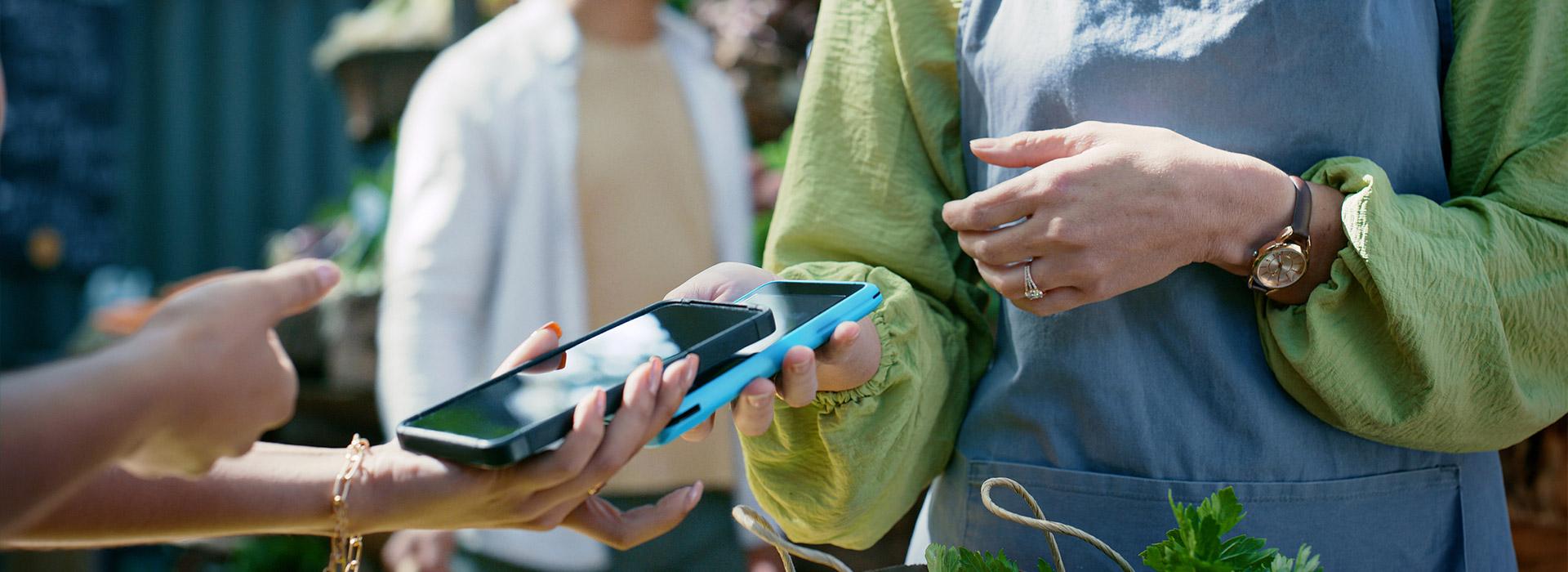 Two people holding cell phones on top of each other