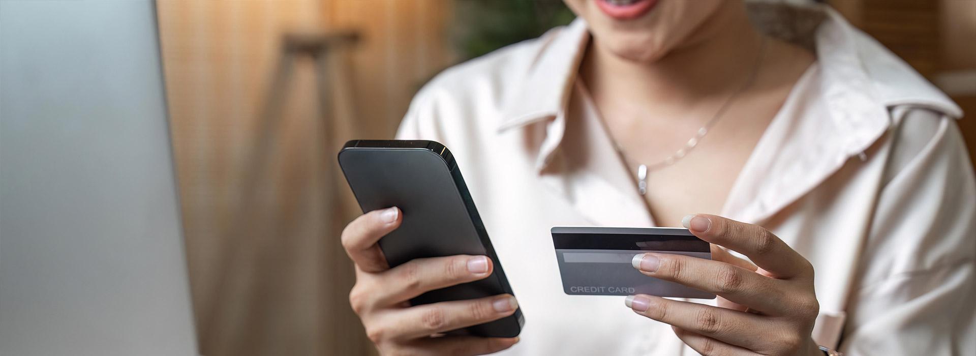 Woman holding credit card in one hand and cell phone in the other