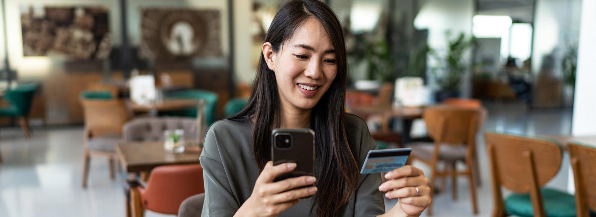 woman looking at her cell phone and credit card