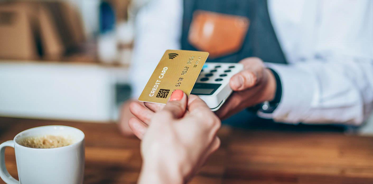 female handing credit card to buy coffee